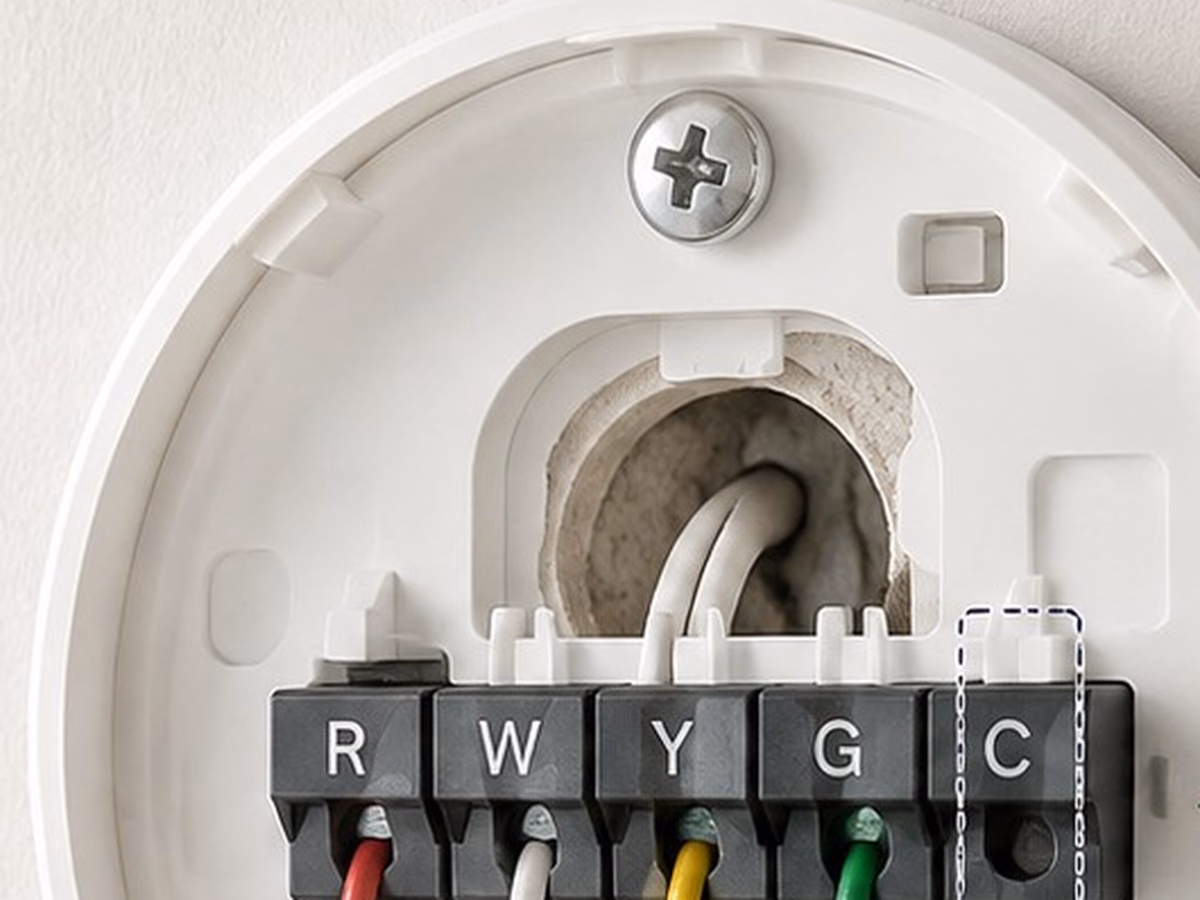 Close-up of a smart thermostat during installation with the wiring terminals visible.